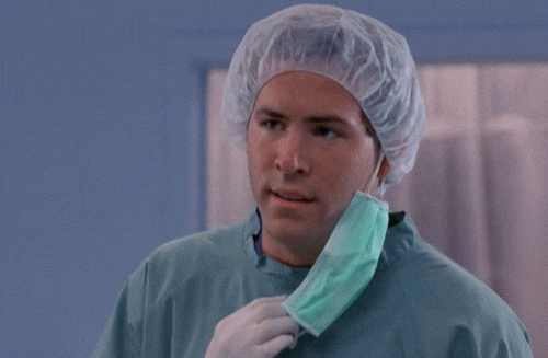 Reaction GIF: a doctor in scrubs pulls down his mask, looking puzzled